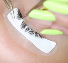 Close up hands master eyelash extension holds pair tweezers his hands pushes cilia apart with these tweezers glue bundle