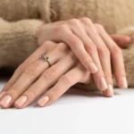 Graceful thin fingers girl with trendy pastel nude manicure fluffy soft sweater cute silver ring bow