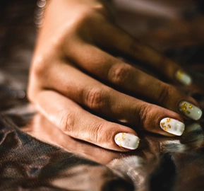 Vertical closeup woman's hand with white manicure
